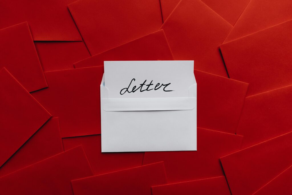 White envelope with letter inside surrounded by red envelopes, flat lay view.