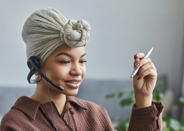 Smiling woman wearing a headset while working at a call center, looking engaged and professional.