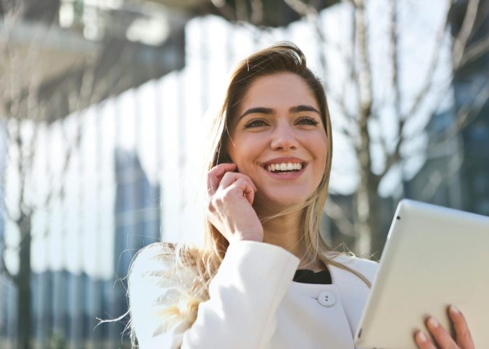 pexels-photo-789822-789822 Confident businesswoman using her tablet and phone, smiling outdoors in sunlight.